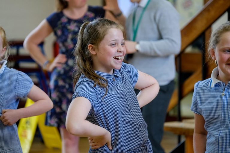 Key stage 2 pupil laughing in Romans drama workshop in school hall