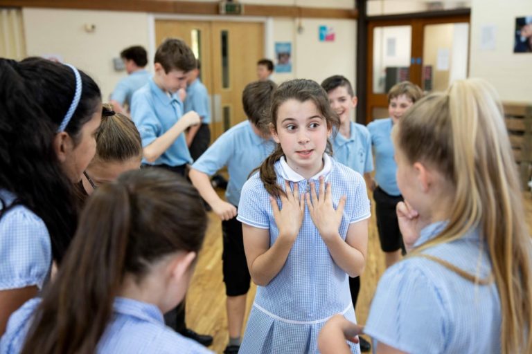 Key stage 2 pupils take part in a drama workshop in their school hall